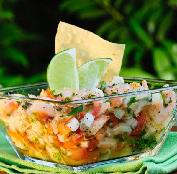 Ceviche in a bowl with lime on a wooden table