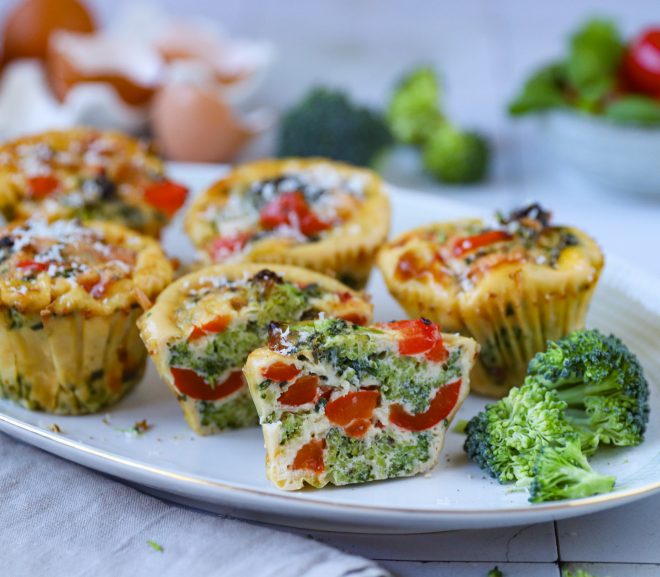 Dozlatova upečené vajíčkové muffiny se zeleninou, bazalkou a čerstvou pažitkou na talíři.