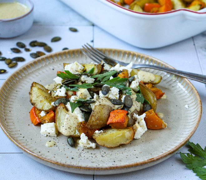 Talíř s pečenými bramborami, oranžovou dýní, sýrem feta a bylinkami posypaný dýňovými semínky.